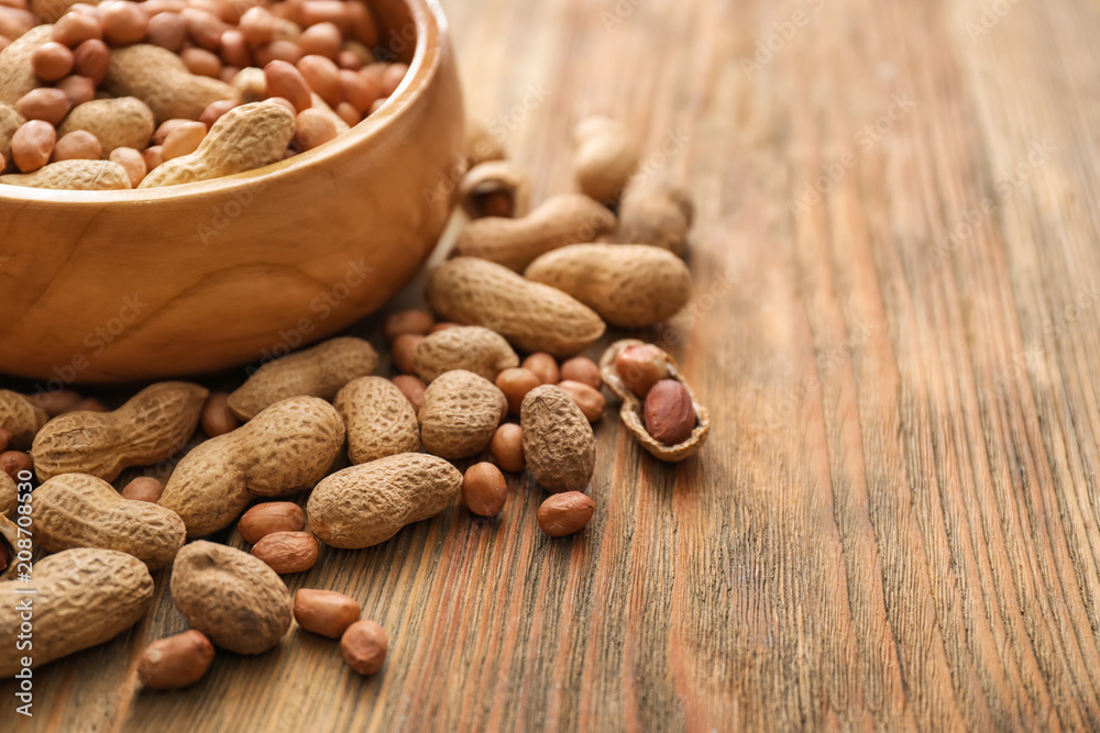 Bowl with tasty peanuts on wooden table Bowl with tasty peanuts on wooden table