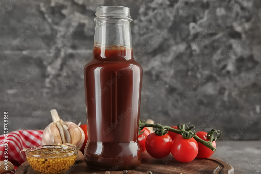 Bottle with tasty tomato sauce and vegetables on wooden board Bottle with tasty tomato sauce and vegetables on wooden board