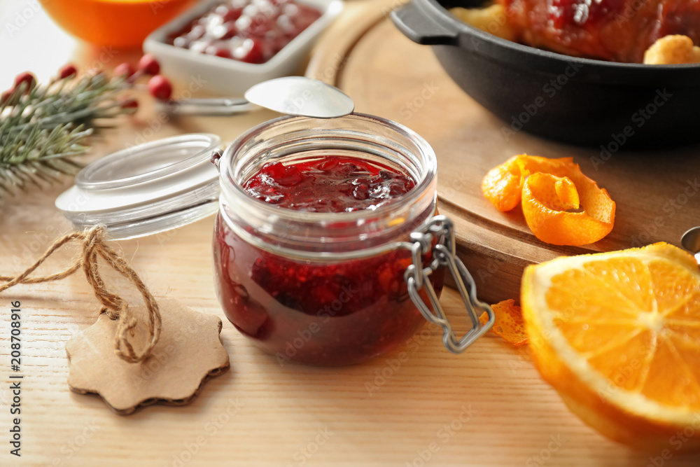 Jar with delicious cranberry sauce and products on table Jar with delicious cranberry sauce and products on table
