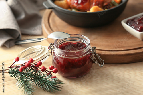 Jar with delicious cranberry sauce on table