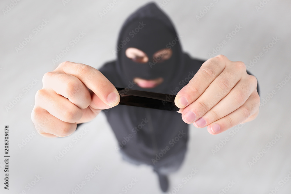 Thief putting sticky tape onto camera of alarm system, indoors Thief putting sticky tape onto camera of alarm system, indoors