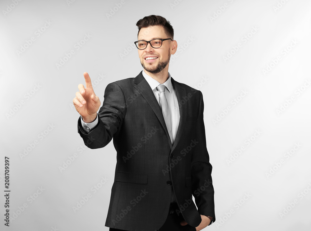 Young businessman using virtual screen on gray background Young businessman using virtual screen on gray background
