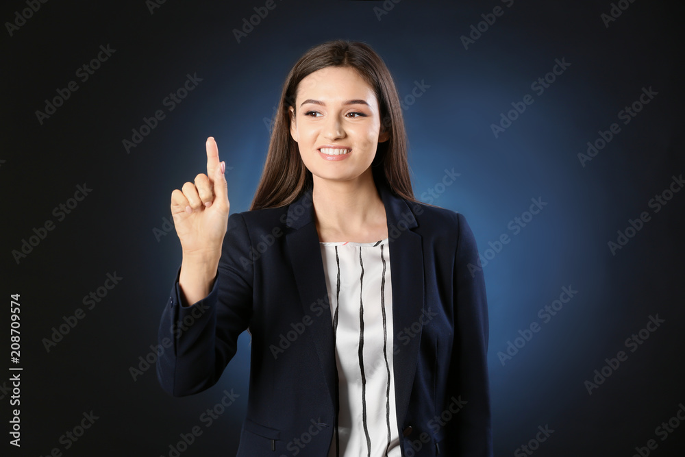 Young businesswoman using virtual screen on dark background Young businesswoman using virtual screen on dark background