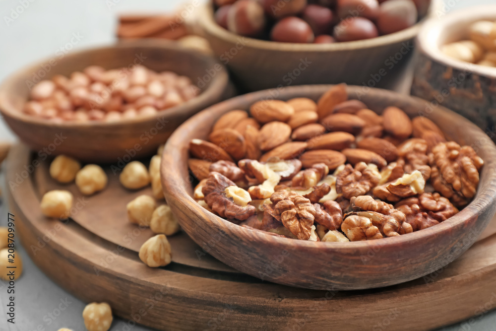 Different kinds of nuts in bowls on table, closeup Different kinds of nuts in bowls on table, closeup