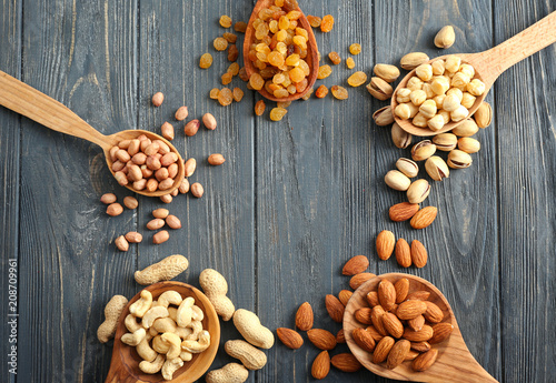 Different kinds of nuts and raisins on wooden background, top view