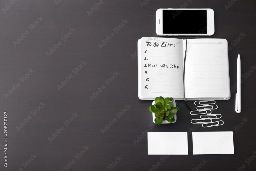 Composition with to-do list and phone on dark background