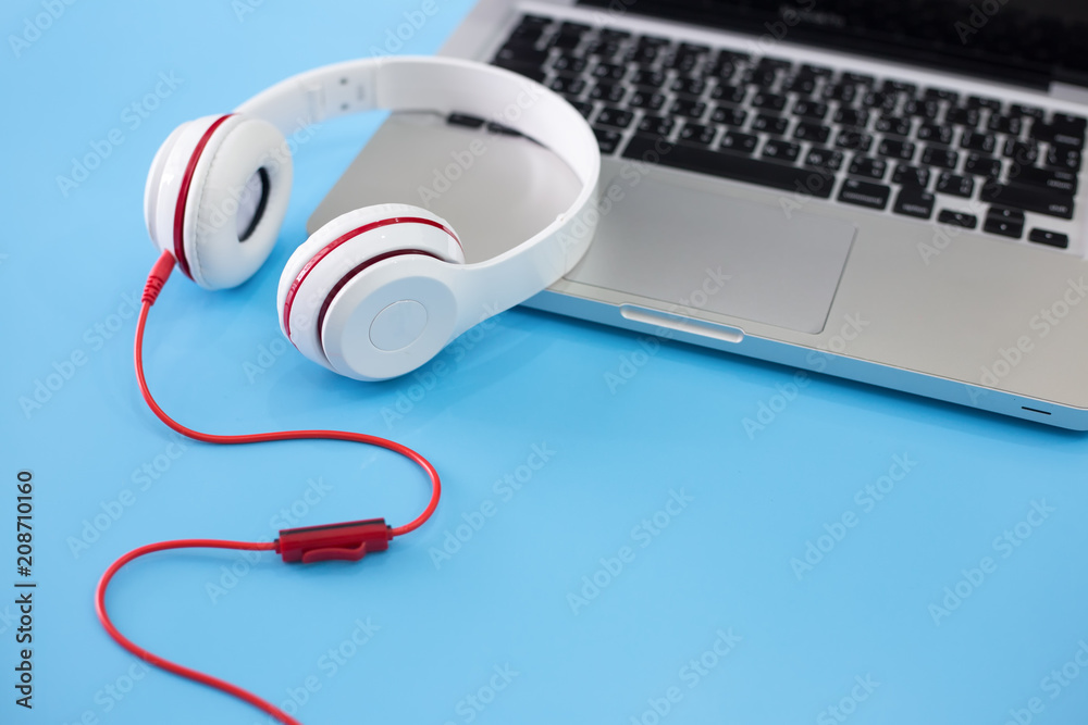 Obraz premium white headphones and laptop on blue background.
