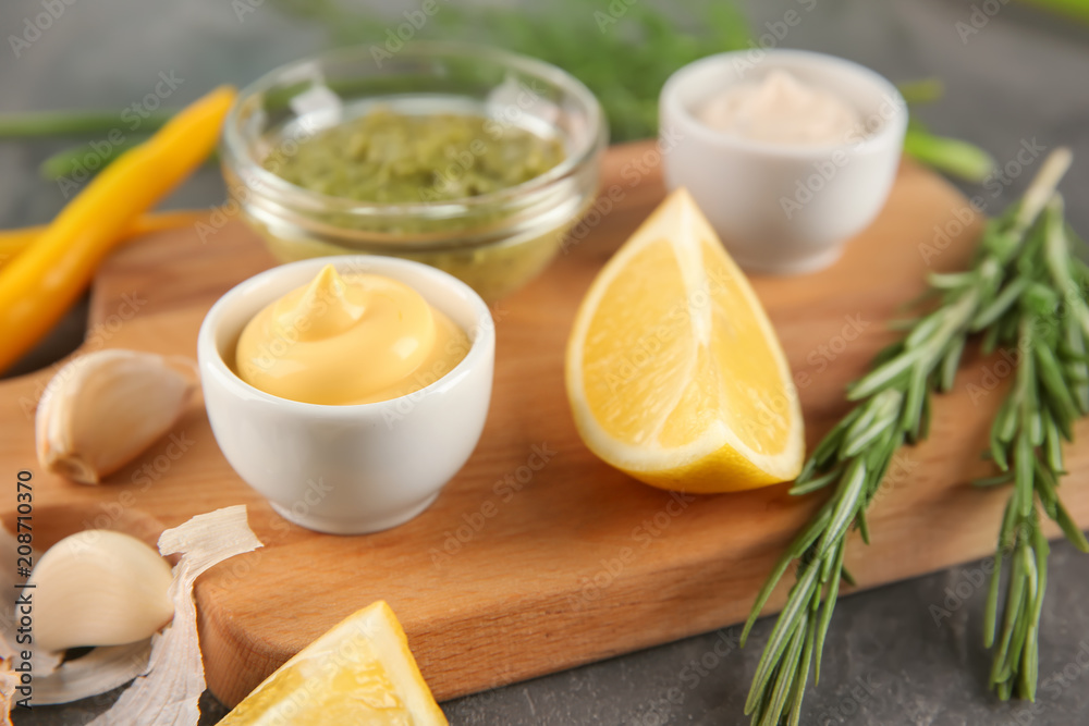 Bowls with different sauces on wooden board, closeup Bowls with different sauces on wooden board, closeup