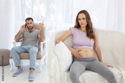 Family during pregnancy. Irritated pregnant woman frowning upon and touching tummy photo