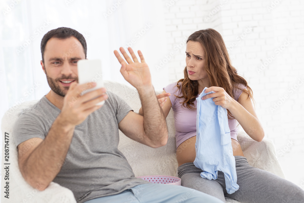 Go away. Joyful man ignoring pregnant woman and gazing at phone screen Go away. Joyful man ignoring pregnant woman and gazing at phone screen