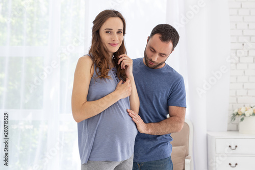 My precious. Pleasant pregnant woman smiling to camer and man touching her tummy
