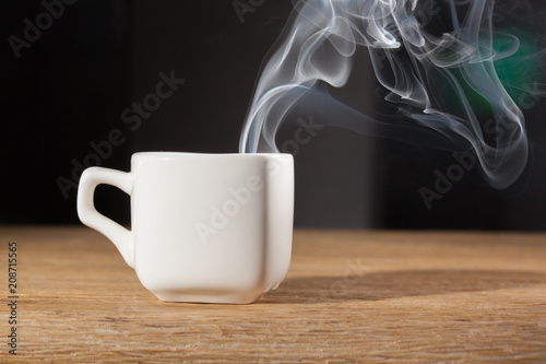 vapor over a cup of morning breakfast on an oak table dark background
