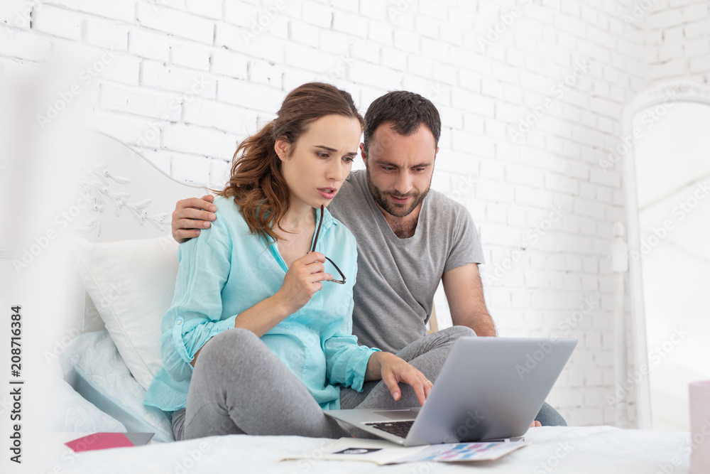 Blog about pregnancy. Low angle of worried pregnant woman and man using laptop and chatting Blog about pregnancy. Low angle of worried pregnant woman and man using laptop and chatting