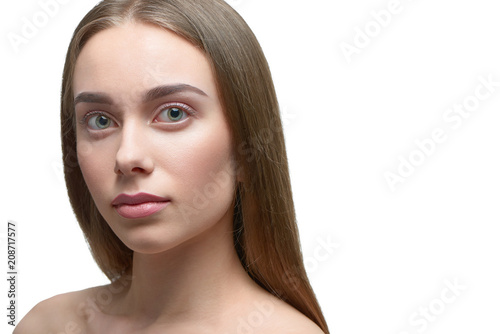 Horizontal photo of girl with light day make up looking at camera. model having beatiful face with nice straight eyebrows, plump lips, big eyes. brown hair, opened shoulders. White studio background.