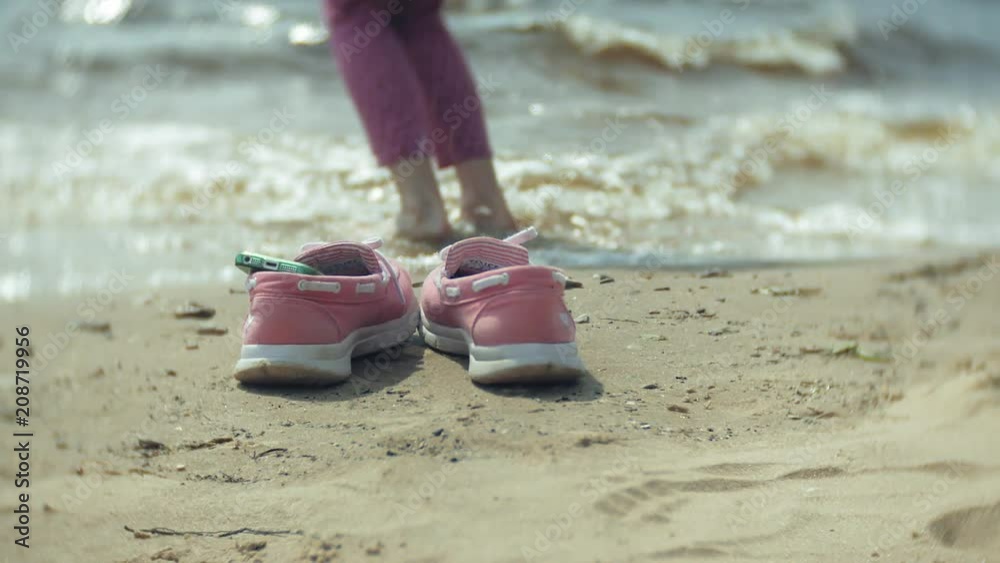 Summer shoes on the beach. in the background of a girl walking and dancing on the sand Summer shoes on the beach. in the background of a girl walking and dancing on the sand