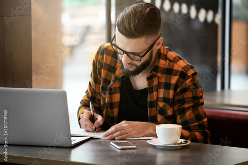 Young freelancer with laptop working in cafe