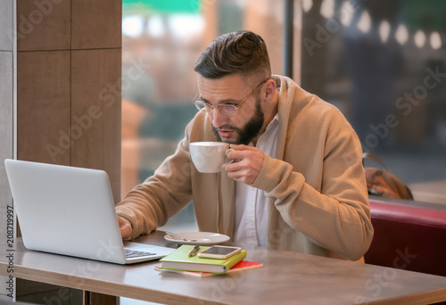 Young freelancer with cup o...