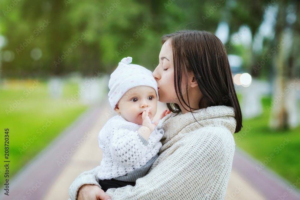 Closeup portrait of mom kissing baby outdoors at park background. Concept of happy family. Closeup portrait of mom kissing baby outdoors at park background. Concept of happy family.
