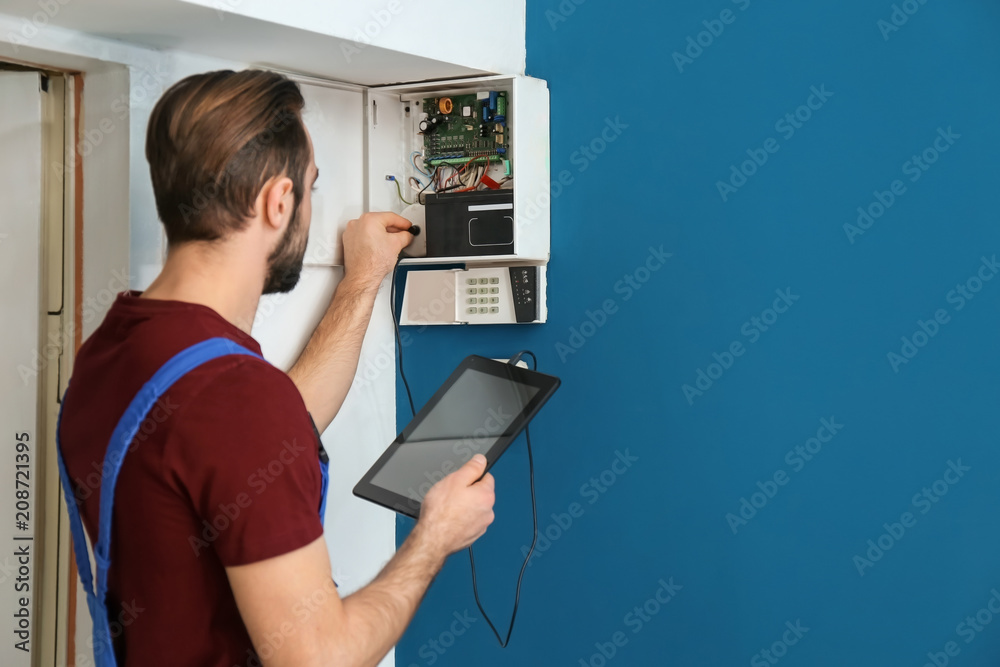Electrician inspecting alarm system - obrazy, fototapety, plakaty 