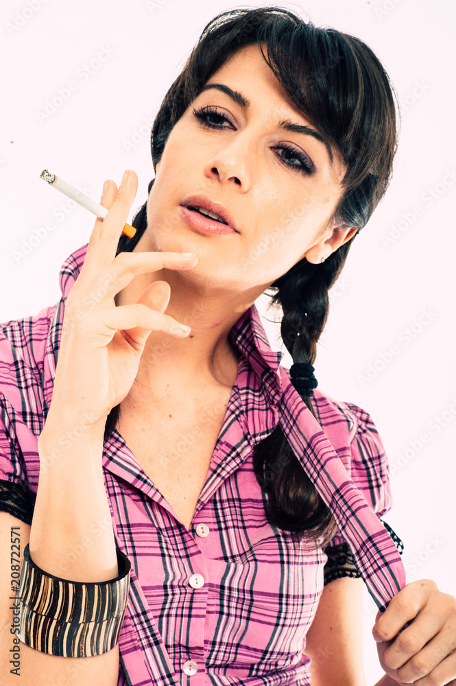 Young caucasian brunette with tail hairstyle smoking a cigarette. White background studio shot. Pink shirt dressed Young caucasian brunette with tail hairstyle smoking a cigarette. White background studio shot. Pink shirt dressed