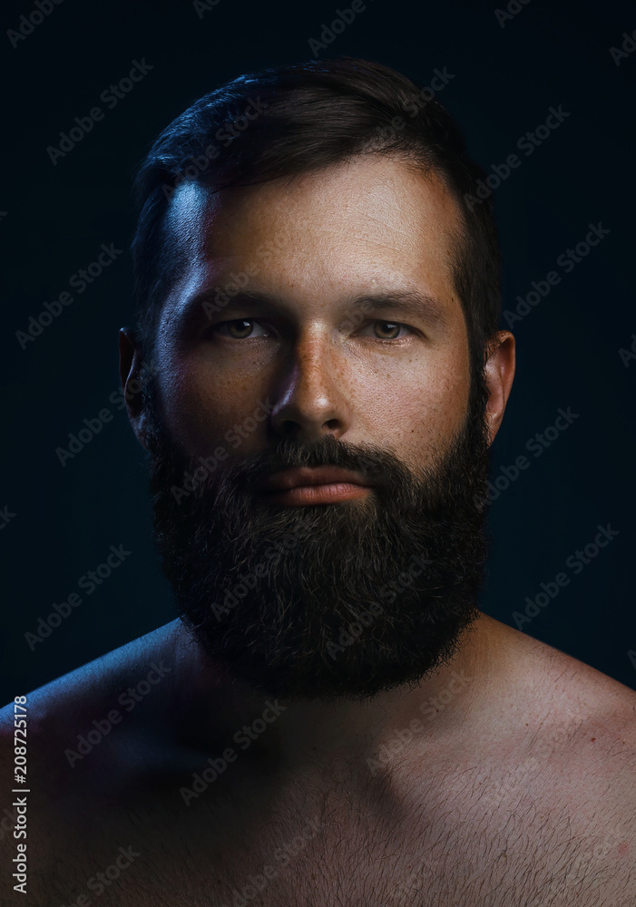 Close-up portrait of a brutal bearded man. Low key dark blue light Close-up portrait of a brutal bearded man. Low key dark blue light