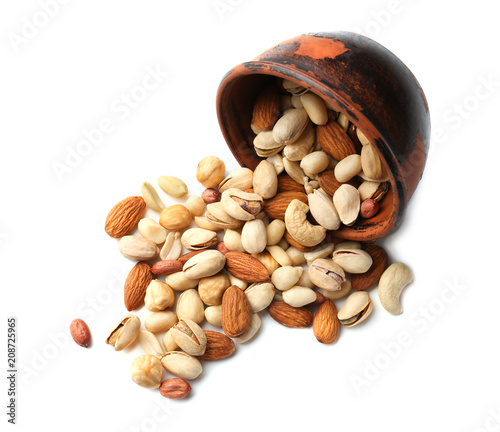 Overturned bowl with scattered nuts on white background