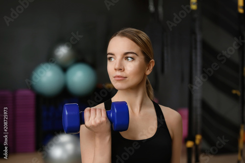Young woman training with dumbbell in modern gym