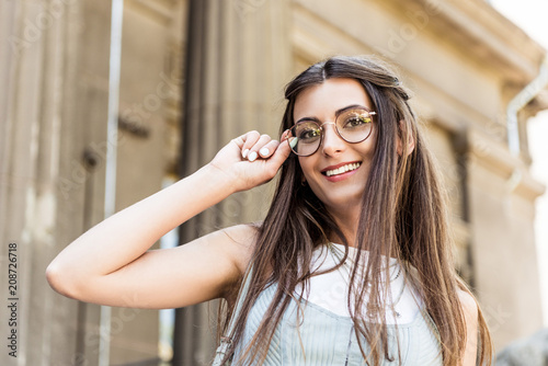 portrait of attractive smiling woman in eyeglasses on street