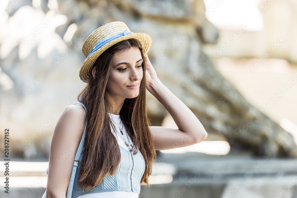 portrait of young thoughtful woman in straw hat on street