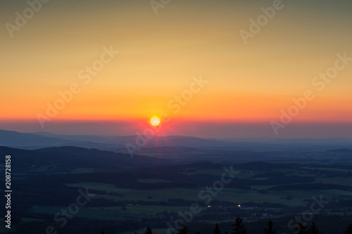 Amazing sunset on hills with small sun from kravi mountains, Czech landscape