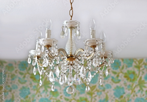 chandelier hanging in front of a floral wallpaper