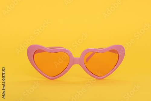 Pink heart shaped sunglasses on a yellow background