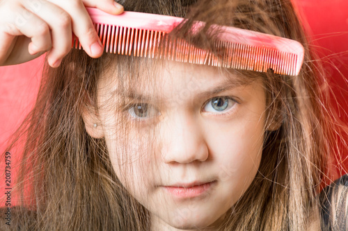 Sweet girl is combing a bang on a red background