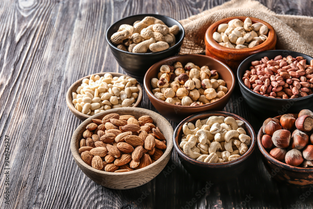 Bowls with different nuts on wooden table Bowls with different nuts on wooden table