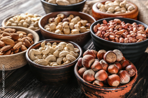 Bowls with different nuts on wooden table