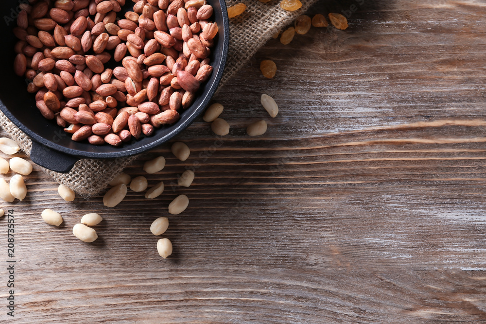 Frying pan with roasted peanuts on wooden background Frying pan with roasted peanuts on wooden background