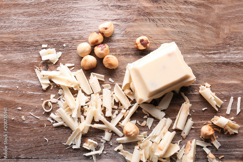 Fotografie White chocolate curls with hazelnuts on wooden table