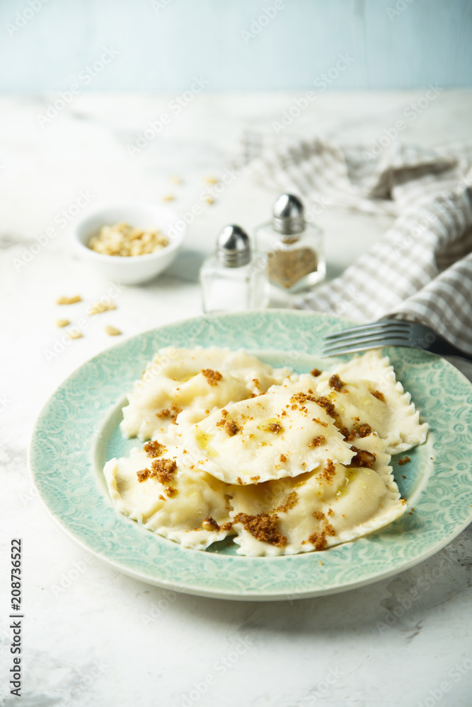 Homemade ravioli with fried bread crumbs, soft cheese and pine nuts