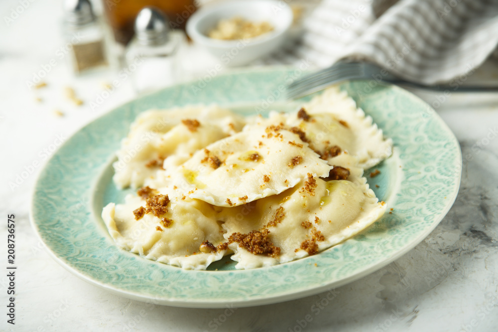 Homemade ravioli with fried bread crumbs, soft cheese and pine nuts