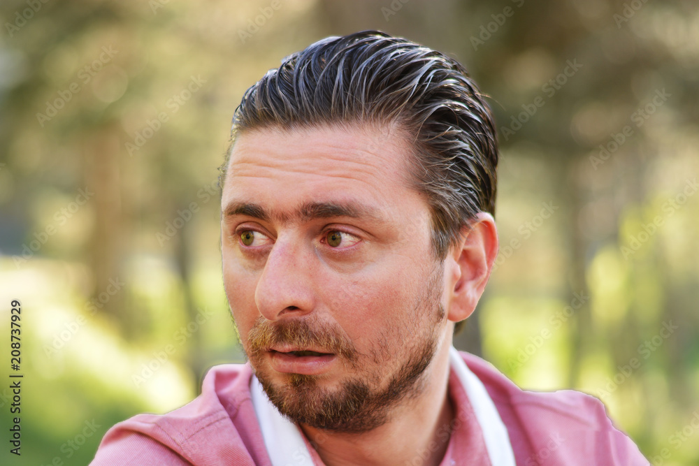 Young man's outdoors portrait looking at the camera with natural green background. Neutral, happy, sad, angry, disgust, fear, surprise Facial Emotions. Young man's outdoors portrait looking at the camera with natural green background. Neutral, happy, sad, angry, disgust, fear, surprise Facial Emotions.