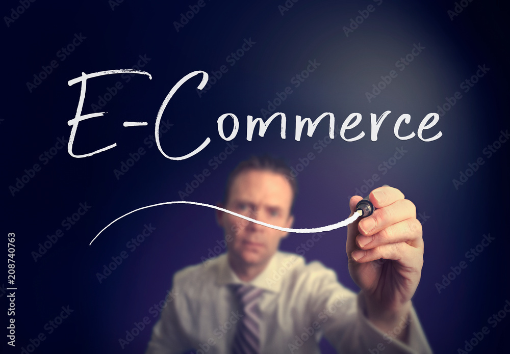A businessman writing a E-Commerce concept with a white pen on a clear screen. A businessman writing a E-Commerce concept with a white pen on a clear screen.