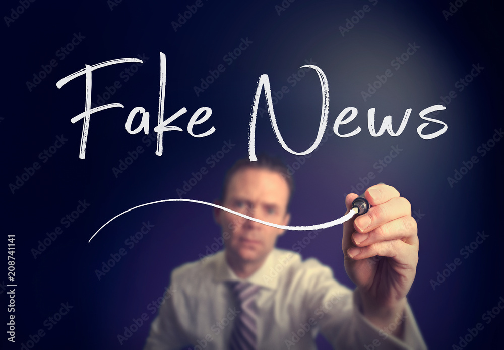 A businessman writing a Fake News concept with a white pen on a clear screen. A businessman writing a Fake News concept with a white pen on a clear screen.