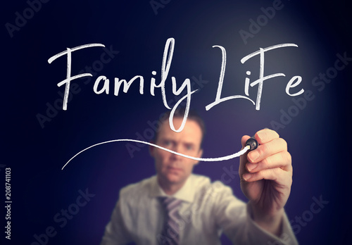 A businessman writing a Family Life concept with a white pen on a clear screen.