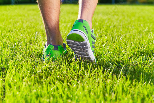 Sports shoes sneakers on a fresh green grass field. Sport equipment bottom view. Sports in the open air.