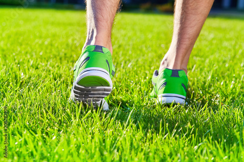 Sports shoes sneakers on a fresh green grass field. Sport equipment bottom view. Sports in the open air.