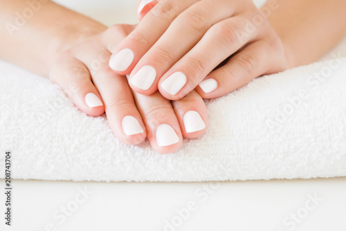Young, perfect woman's hands with white nails on towel. Care about nails and clean, soft, smooth skin. Manicure, pedicure beauty salon.