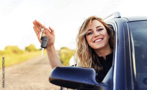 Obraz na płótnie An attractive woman in a car holds a car key in her hand. w salonie