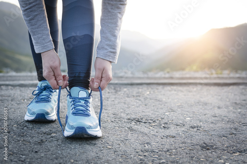 Sport runner woman tying laces before training. Marathon.