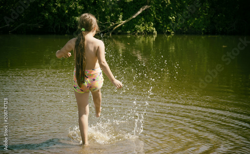 A little girl splashing her foot in the water. Children and summer holidays.