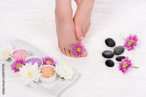 cropped image of barefoot woman on spa treatment with flowers  colorful sea salt and spa stones